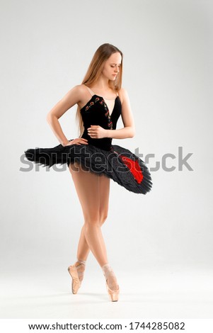 Girl in a black ballet dress. Ballerina in a dark ballet tutu on a light background. The young ballerina is warming up