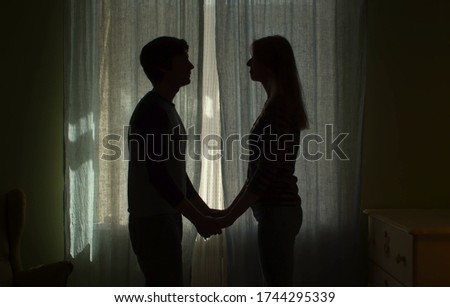 Silhouette of couple near the window. Family holding hands. The curtains are closed in the room