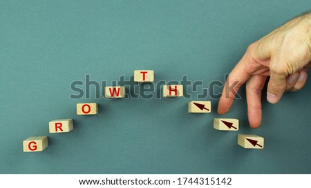 Business success growing growth increase concept. Forest wooden blocks with the hand of a young man on an olive background with the word GROWTH.