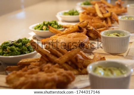 Fish & chip meal with peas on wooden plating board. Tasty meal dinner seafood. 