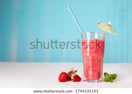 summer soft drink, strawberry, smoothie, fresh with a straw and umbrella, on a blue background Royalty-Free Stock Photo #1744335101