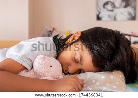 Little girl sleeping on her bed inside her room Royalty-Free Stock Photo #1744368341