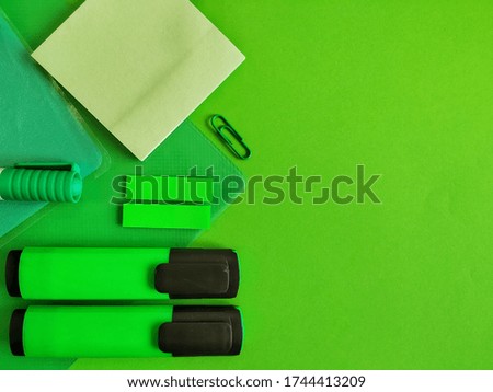 Marker, paper clip, copybook and pen on a green background, the concept of a modern workspace