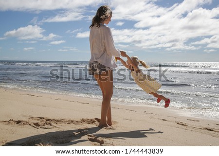 Mother enjoying a day at the beach with her little toddler girl. Happy family vacation concept.