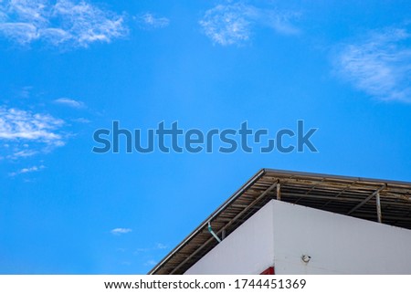 Low angle picture a corner roof on a building against blue sky with clouds in summer day.