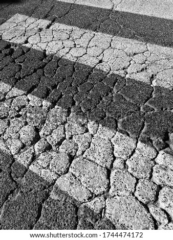 Crosswalk detail, for crossing, with old asphalt worn by traffic and weather