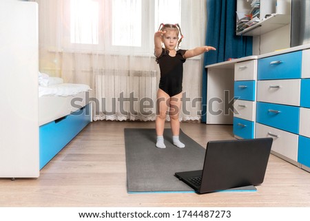the child does gymnastics on a gymnastic rug at home in front of a computer. sports distance learning. space for text, copy space