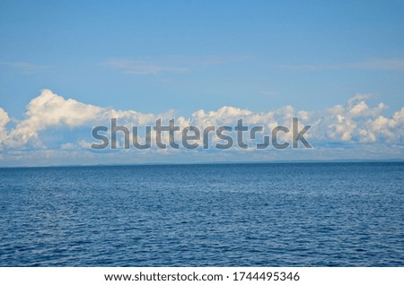 Bright, blue sky with white clouds over a calm lake on a sunny day. Horizontal photo, travel concept