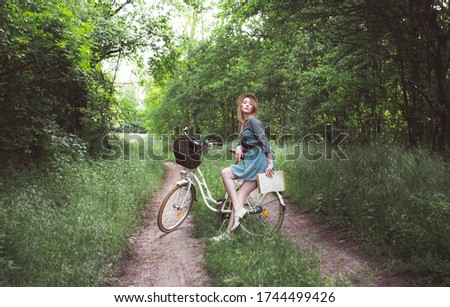 Portrait of a young woman riding an old bicycle.