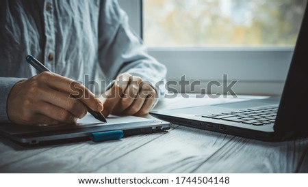 Modern work place at home for artist or photo editor with black computer and graphic tablet on light window background