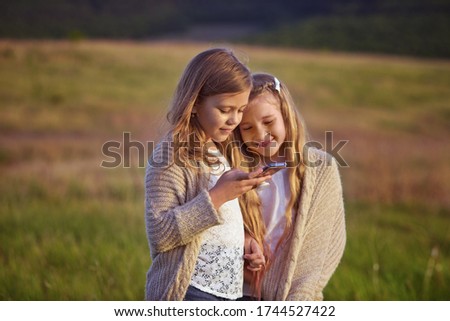 two funny happy girls with phone outdoors