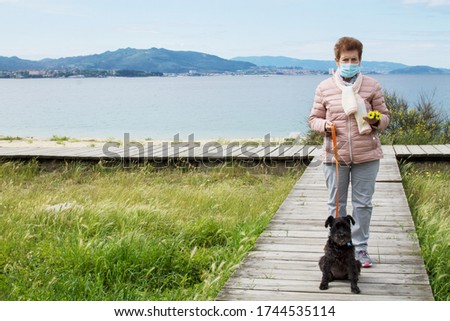 senior woman with medical mask walking with her dog