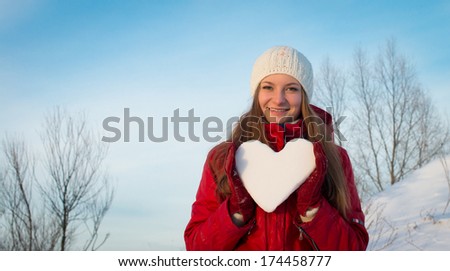 Attractive smiling young girl holding a snowy heart.