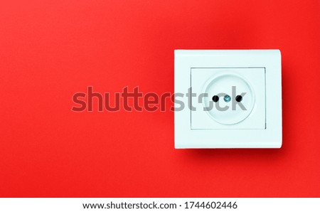 White plastic power socket on red background. Wall with copy space. Minimalism.