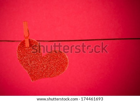 decorative red heart hanging on red background with space for text, concept of valentine day