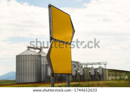 Agricultural Silos, Storage and drying of grains. Yellow empty sign. Wheat, corn, soy, sunflower against the blue sky with rice fields.