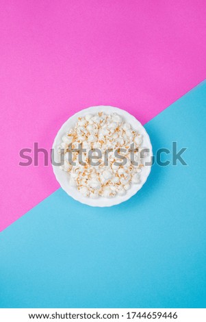 White bowl of popcorn on a blue and purple background
