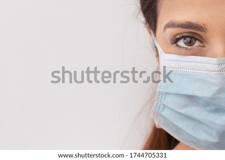 Brunette girl with white t-shirt wears a surgical face mask, isolated on white background