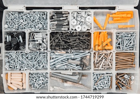 Case with small construction objects. Set metal tool box of screws, anchors, nails, bolts.