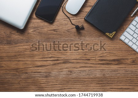 Business and education concept. Flat composition with keyboard,
lapel microphone, smartphone, notepad and other office objects on a wood background