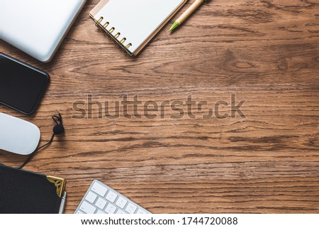 Flat composition with keyboard,
lapel microphone, smartphone, notepad and other office objects on a wood background