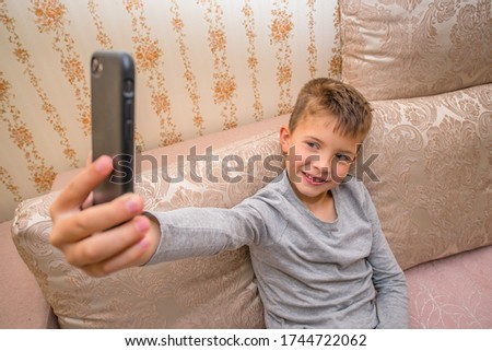 little boy takes a selfie at home on the couch. photo on the page. happy boy.