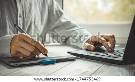 Modern work place at home for artist or photo editor with black computer and graphic tablet on light window background