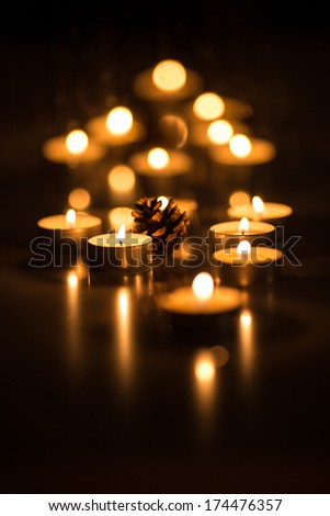Bokeh picture of tea candles and a pine cone