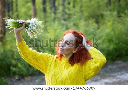 close up red haired pretty girl posing with bouquet of white flowers in yellow sweater. gentle image young woman