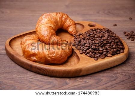 Coffee beans and croissants on wood