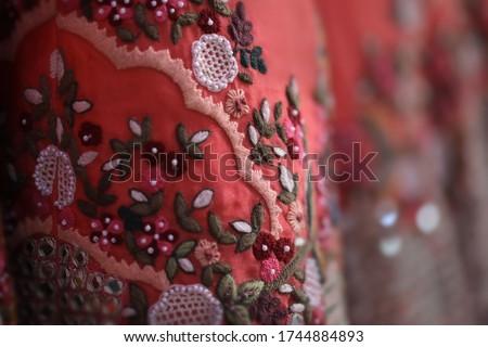 close up of lovely wedding skirt called lehenga, an Indian traditional wedding clothing in pink and red color with golden and crochet like flower embroidery in a blurred background Royalty-Free Stock Photo #1744884893