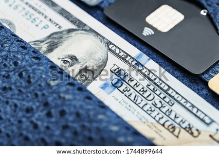 Blue purse with banknotes and credit cards on a black background.