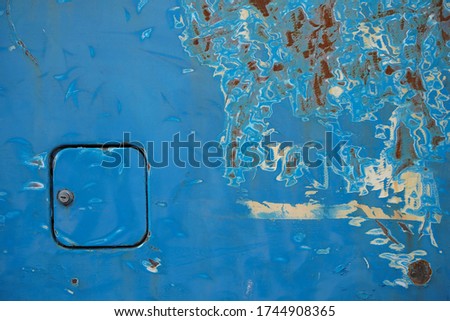 Poor quality paint on the car, cracks and scratches on the rusty metal surface. Abstract pattern, texture, pattern detail background with rusty stains. Of a petrol cap cover on a old blue car