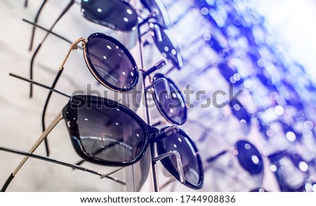 Sunglasses in the shop display shelves. Stand with glasses in the store of optics. Sales rack of sunglasses. A colorful display of sunglasses for sale. Closeup.