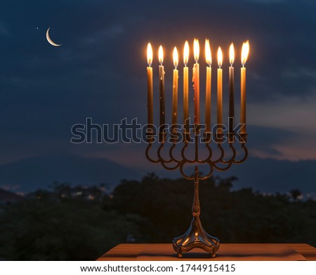 Low key image with menorah and glitter lights of burning candles. Image symbolizes Jewish holiday of Hanukkah. Selective focus
