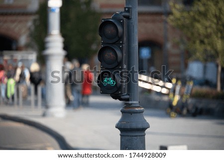 Traffic light with a bicycle icon, green light. Urban transport. Street with people on a blurred background