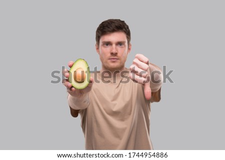 Man Showing Avocado and Thumb Down Close Up Isolated. Avocado Cut in Half. No Avocado, Stop Avocado Concept