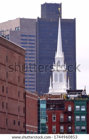 Tall white steeple of historic New England landmark Old North Church (Christ Church) framed by modern Boston skyline. Built in 1723, the oldest church building in Boston.