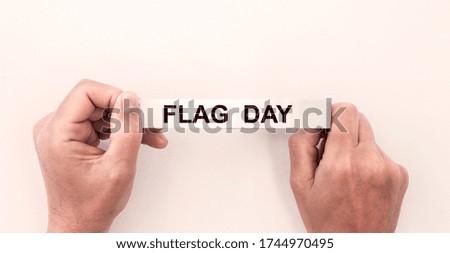 Flag day text inscription on white tape in hands on white background