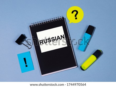 Word Russian on notebook with stickers and markers around on blue table. Business and language educational concept concept