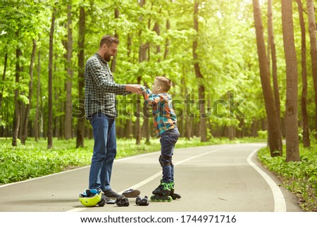 Father and son in the open air, preparing for roller skating. Father's Day. 