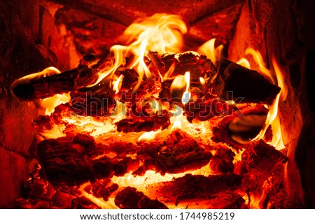 Burning firewood in red flame. Sparks fly in different directions