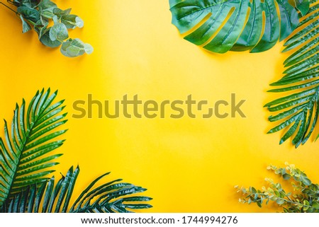 Tropical palm leaves on yellow background. Flat lay, top view