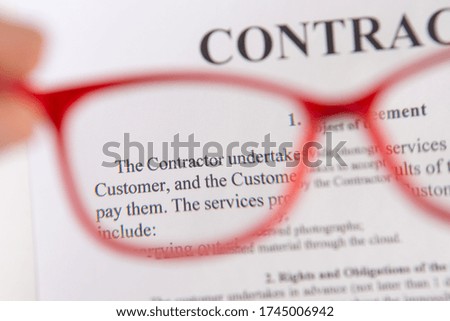 Close up of contract with red reading glasses in hand