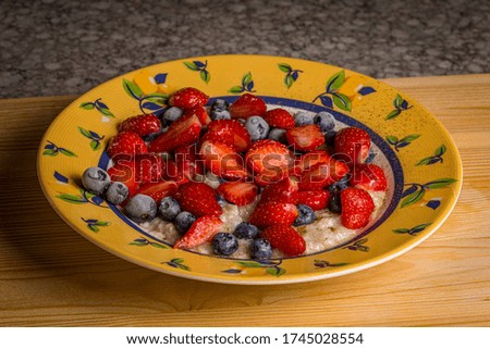 Healthy breakfast - Oatmeal with fresh strawberries and frozen blueberries with cinnamon on a table in a plate