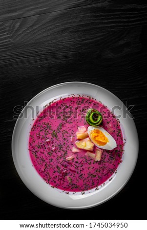 Vegetable cold soup with beet, cucumber, radsih and egg on black wooden table