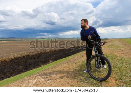 Bearded cyclist on a mountain bike in a field