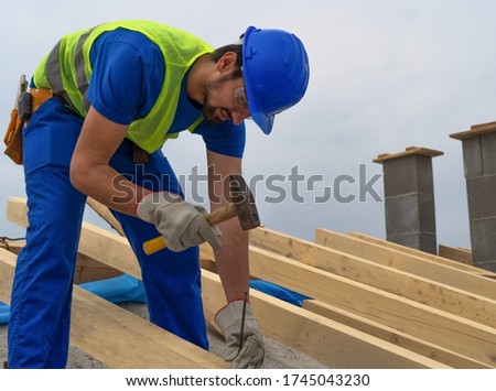 A construction site worker nails a nail on to the roof of a building stock photo