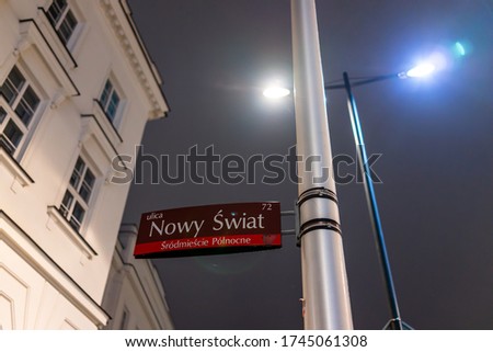Nowy Swiat (New World) street sign in old town by historic Krakowskie Przedmiescie street at night with lamp post in Warsaw, Poland
