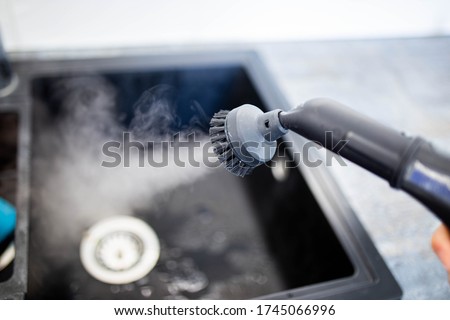 cleaning the sink and faucet with a steam cleaner, disinfection in the house. Royalty-Free Stock Photo #1745066996